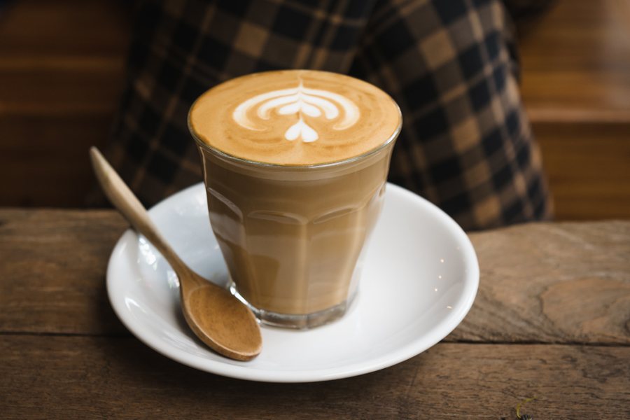Un latte dans un verre, une feuille dessinée dans la mousse