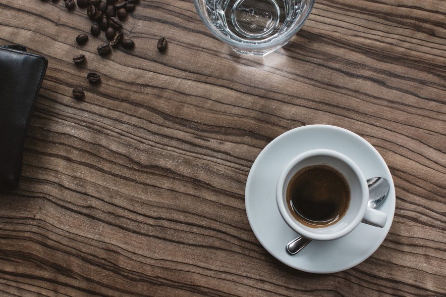 Un espresso vu d’en haut sur une table de bois, des grains de café autour