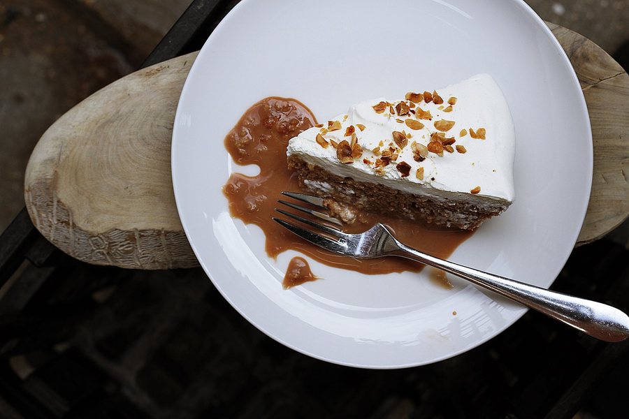 Une part de gâteau sous la crème et les noix, nappée de caramel