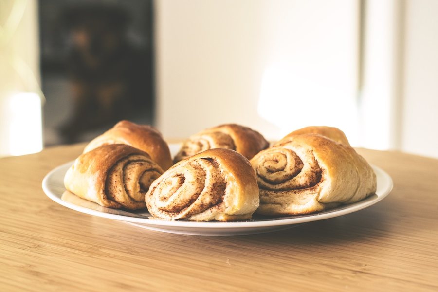 Des roulés à la cannelle dorés sur une assiette blanche